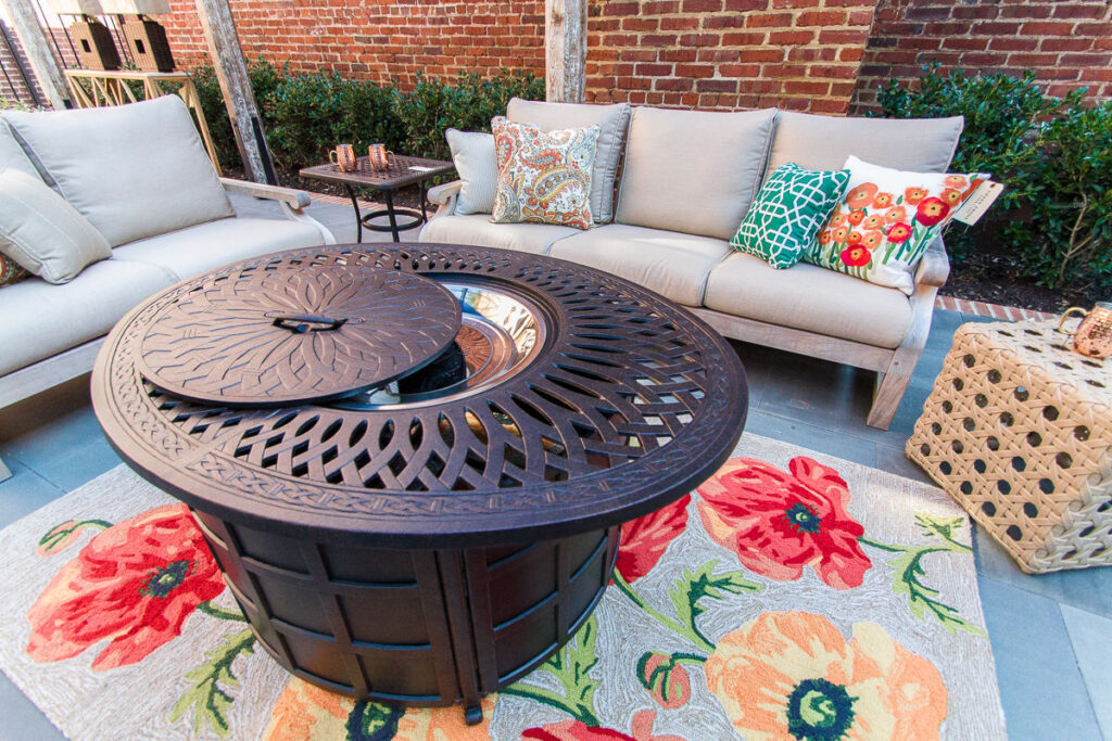 brown metal fire pit on a floral rug in front of two beige couches